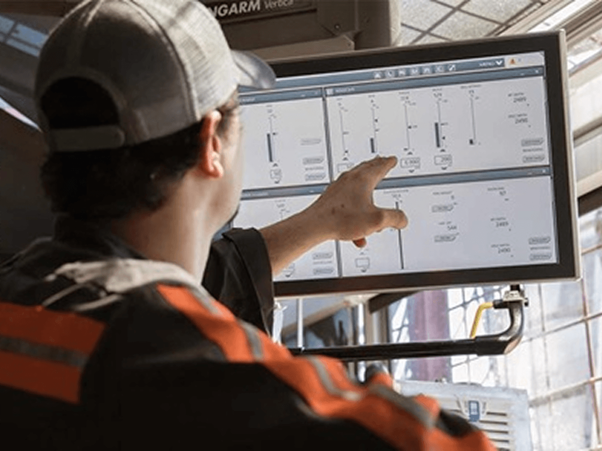 A field worker pointing at real-time tank data on a rig-side monitor